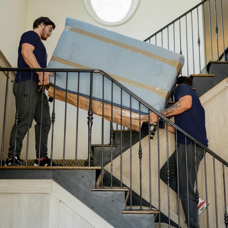 A Motivated Movers professional securely carries furniature up the stairs, showcasing expert moving and handling skills.