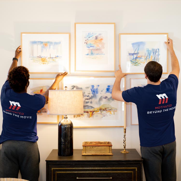 Dedicated Motivated Movers employee hangs pictures in a new home, ensuring a full-service moving experience.