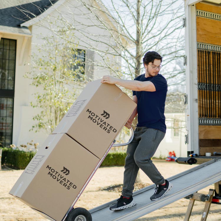 A Motivated Movers staff member efficiently loads boxes on a dolly, highlighting efficient packing services.