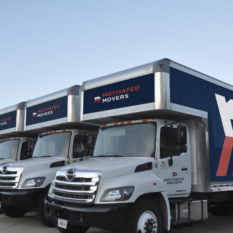 Motivated Movers trucks lined up, ready for dispatch, representing the company's preparedness for comprehensive moving solutions.